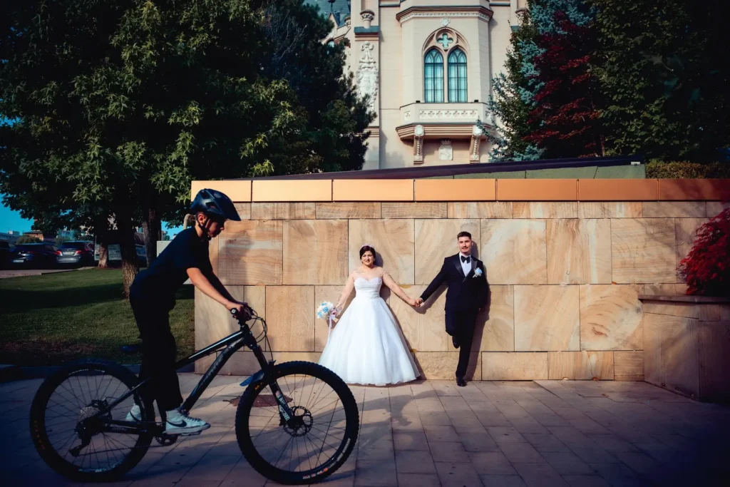 Cadru documentar de nuntă la Palatul Culturii din Iași, surprinzând mirii și un biciclist în trecere, ilustrând stilul autentic Clipe Dragi.